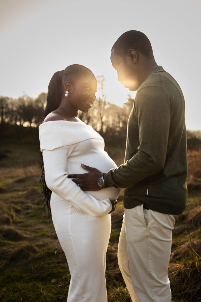 Expectant father holding his partner’s bump at golden hour during an outdoor maternity photoshoot in Mugdock Country Park, Glasgow