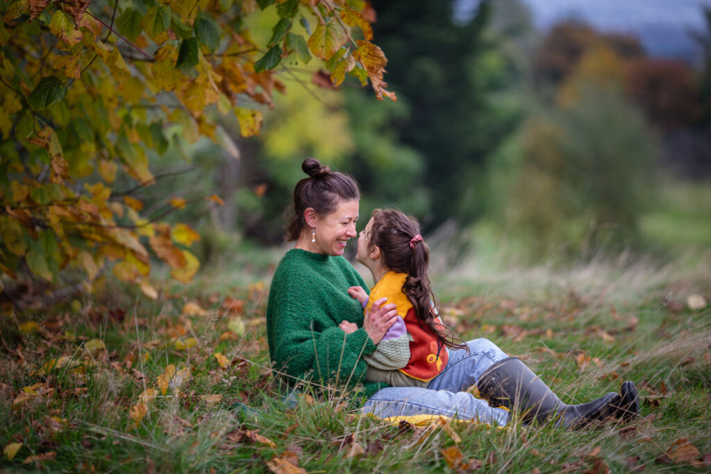 Mother and daughter sharing a laugh during an outdoor family photo session in Glasgow, Scotland. Family photographer capturing authentic family memories and real connection.