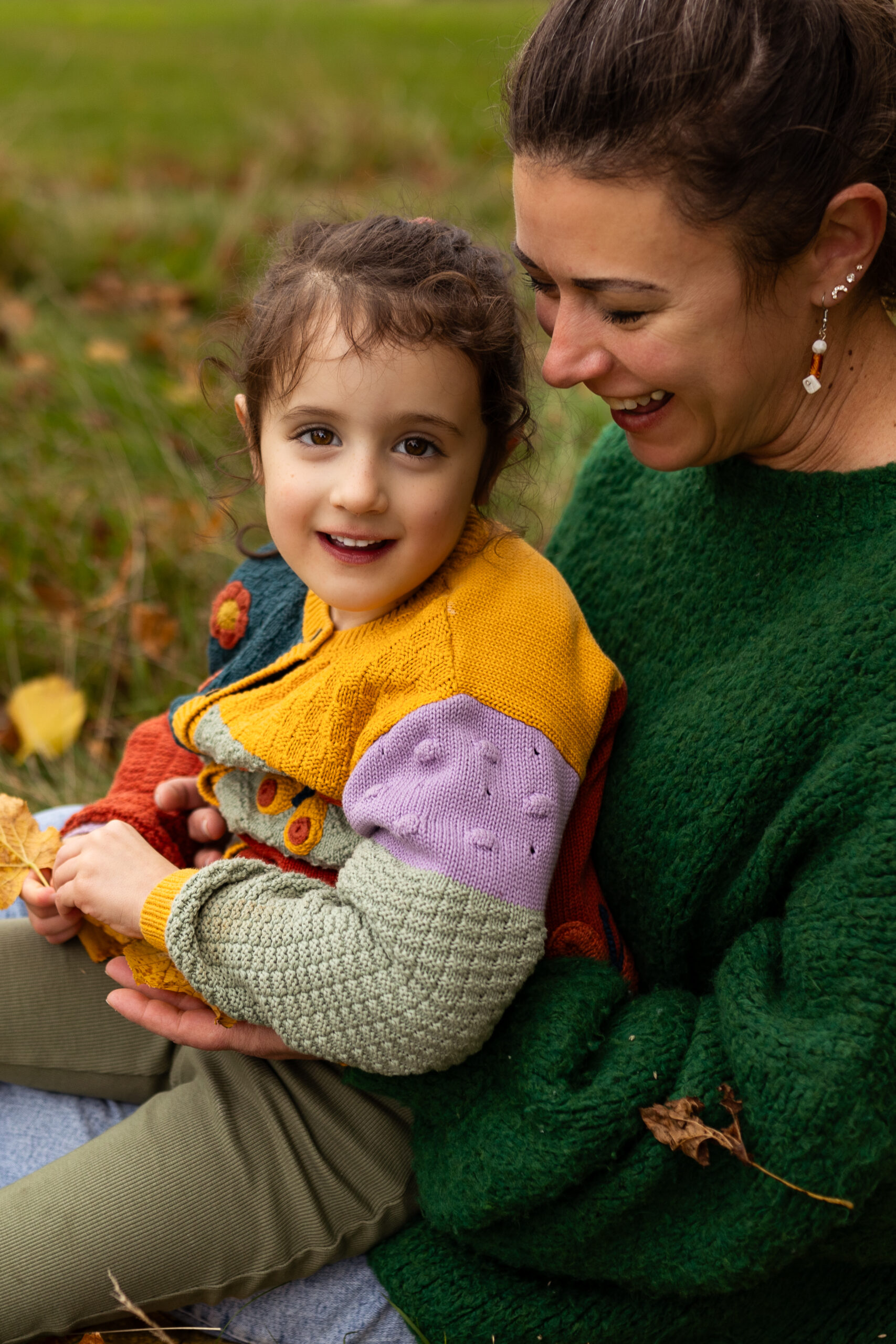 Mother and daughter sitting together in a meadow during a family photography session in Glasgow. Lifestyle family portraits capturing authentic relationships and childhood memories.