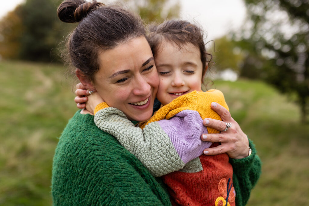 Mother cuddling her daughter after a playful chase during an outdoor family photoshoot in Glasgow.