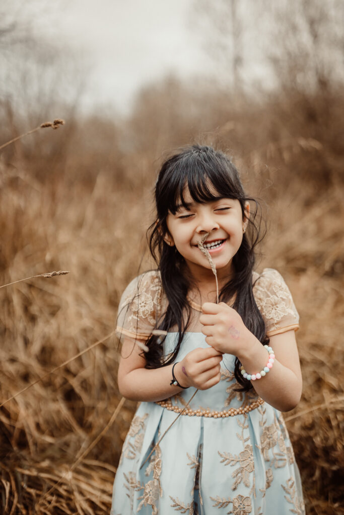 Mother and daughter laughing together in a meadow during an outdoor family photography session in Glasgow. Lifestyle family photographer capturing authentic family memories in Scotland.