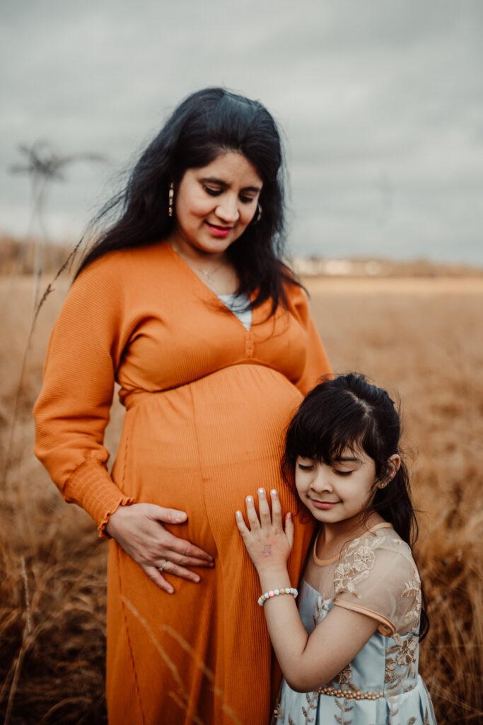Mother and daughter laughing together in a meadow during an outdoor family photography session in Glasgow. Lifestyle family photographer capturing authentic family memories in Scotland.