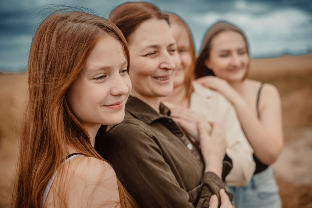 Mother and her three daughters sharing a special moment during an outdoor family photoshoot in Scotland. Natural family photography focused on genuine emotion and meaningful family connections.