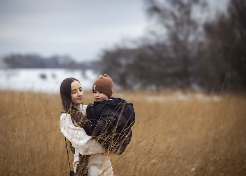 sister holding her younger brother in tall winter grass during an outdoor family photoshoot in Glasgow