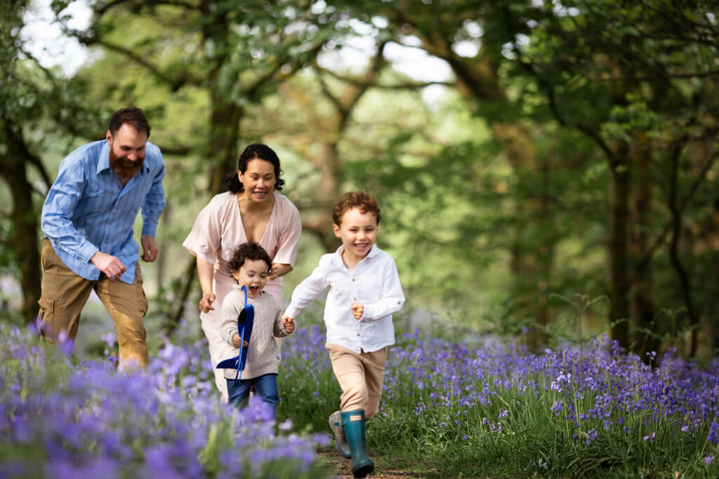 Parents and children running together during a spring bluebell family photoshoot in Glasgow
