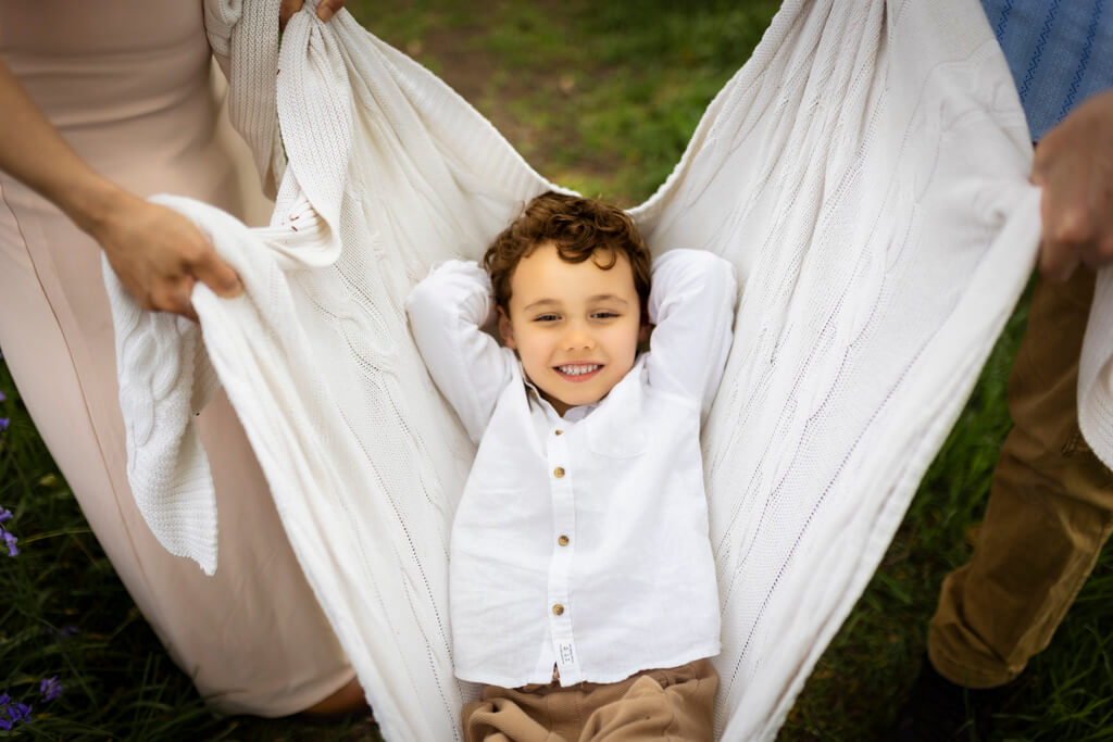 Boy sitting in a blanket swing during a family photoshoot in Glasgow