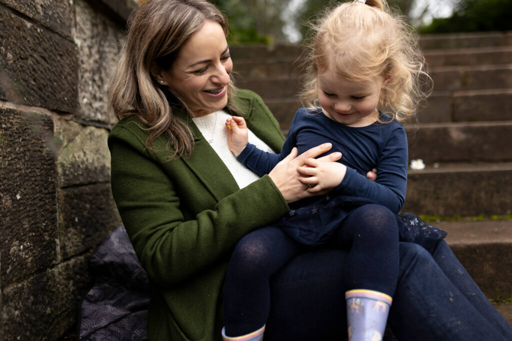mother and daughter laughing on stone steps during a natural family photoshoot