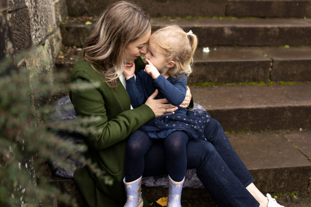 mum cuddling her daughter on stone steps during an autumn family photoshoot