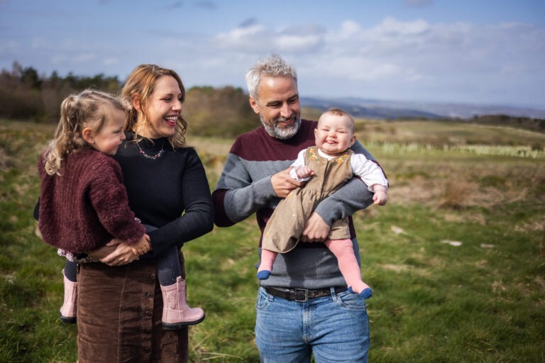 Parents holding their newborn baby and older sibling during an autumn family photoshoot in Glasgow