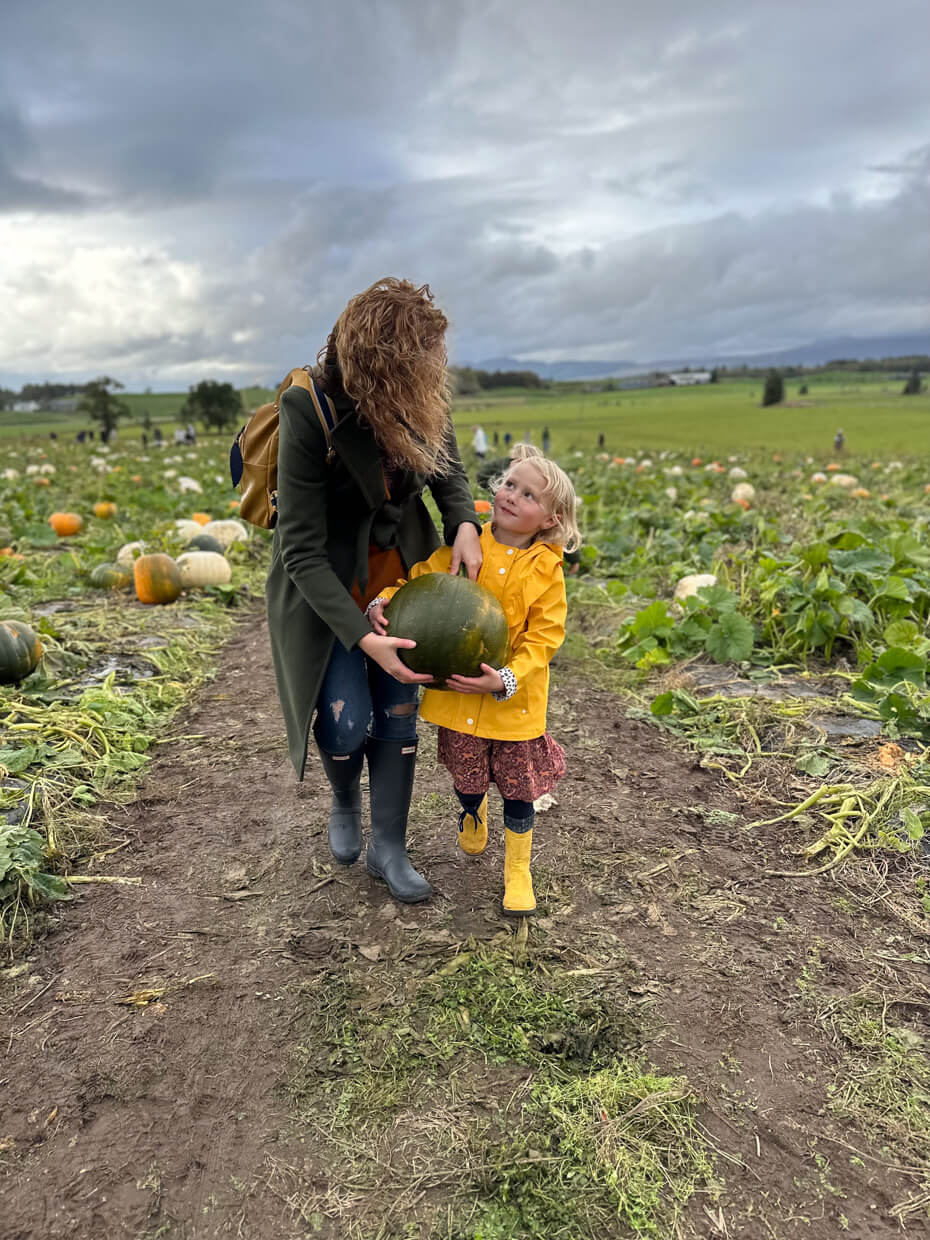 Mum and children choosing pumpkins together during an autumn pumpkin patch visit