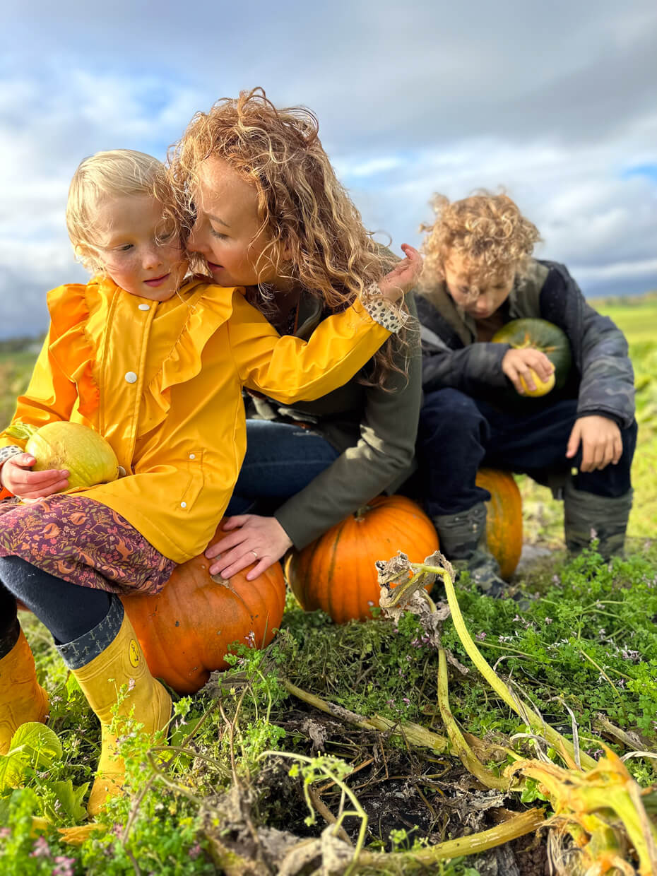 Mum and children choosing pumpkins together during an autumn pumpkin patch visit