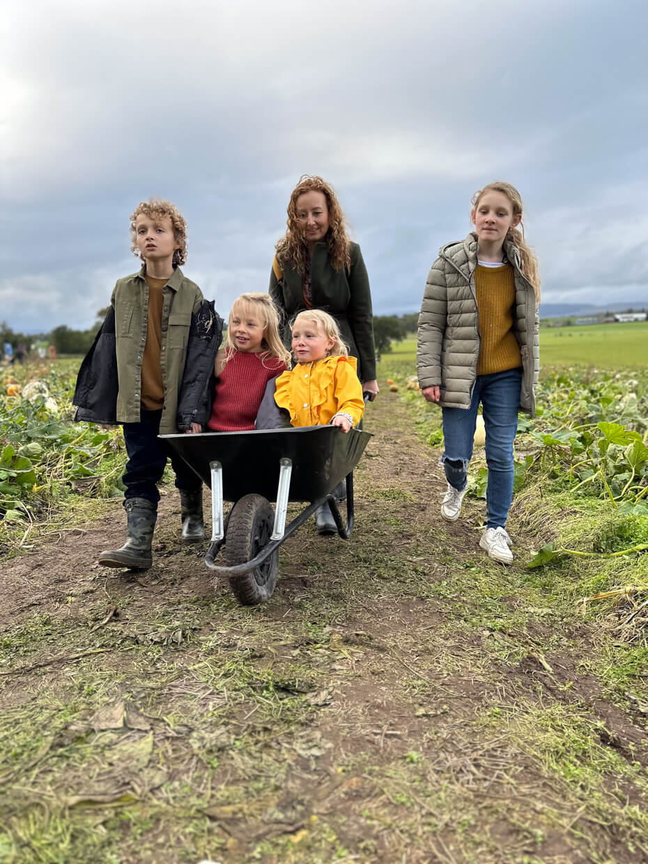 Mum and children choosing pumpkins together during an autumn pumpkin patch visit