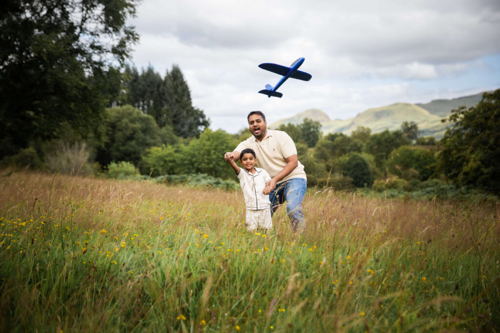 Father and son playing with an aeroplane during a summer family photoshoot in Glasgow.