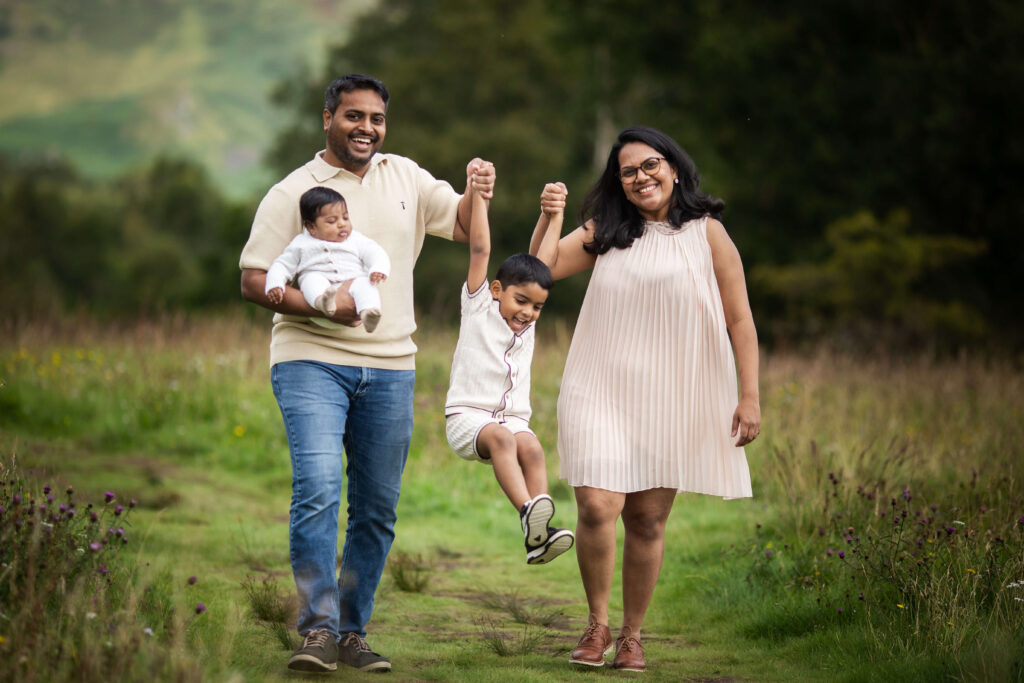 Family with a newborn and young boy during a summer outdoor family photoshoot in Glasgow, wearing coordinated neutral beige outfits