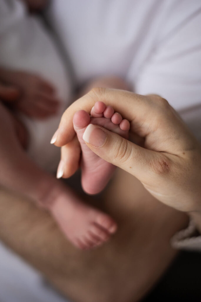 Parent's hand gently holding a newborn baby's tiny foot